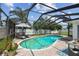 Screened-in pool area features a relaxing lounge area, mature landscaping, and an umbrella for shade at 3545 59Th N Ln, St Petersburg, FL 33710