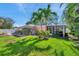 Backyard featuring a screened-in patio, beautiful landscaping, and mature palm trees at 3898 49Th S Ave, St Petersburg, FL 33711