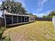 Wide backyard with grassy area, mature trees, and a screened-in patio, offering plenty of room for activities at 3902 Glissade Dr, New Port Richey, FL 34652