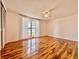 Spacious bedroom with hardwood flooring, ceiling fan, and a large window allowing lots of natural light at 3902 Glissade Dr, New Port Richey, FL 34652
