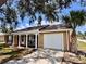 Inviting home showcasing a covered front porch, a garage, and lush landscaping at 3902 Glissade Dr, New Port Richey, FL 34652