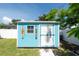 Quaint backyard shed painted blue with white trim, a window, and tropical decorations near a garden and fence at 4718 24Th S Ave, St Petersburg, FL 33711