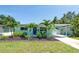 Charming, light-blue single Gathering home featuring lush landscaping, a well-manicured lawn, and a covered carport at 4718 24Th S Ave, St Petersburg, FL 33711