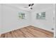 Bright bedroom featuring hardwood floors, a ceiling fan, and two windows providing ample natural light at 4731 W Leila Ave, Tampa, FL 33616