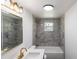 Updated bathroom featuring grey tile, modern fixtures, and a bright vanity area, offering a clean and stylish design at 4823 Ashland Dr, Tampa, FL 33610