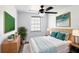 Bright bedroom with a ceiling fan, window and a bed with teal and cream colored pillows at 4823 Ashland Dr, Tampa, FL 33610