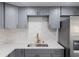 Renovated kitchen featuring gray cabinets, stainless steel appliances, and stone countertops and backsplash at 4823 Ashland Dr, Tampa, FL 33610