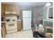 Compact kitchen with white appliances, wood cabinets, and a small dining area at 5541 Bay Blvd # 204, Port Richey, FL 34668