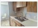 Kitchen with stainless steel sink, wood cabinets, and view into small dining area at 5541 Bay Blvd # 310, Port Richey, FL 34668