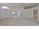 A bright, spacious living room featuring high ceilings, neutral carpet, and an open layout to the kitchen at 602 Deep Lake Ln, Sun City Center, FL 33573