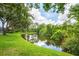 Backyard pond view featuring serene water, green grass, and mature trees at 6044 Sandhill Ridge Dr, Lithia, FL 33547