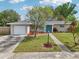 Charming home with a well-manicured lawn, colorful landscaping, and an attached garage at 6167 31St Ave, St Petersburg, FL 33710