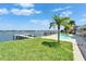 Backyard featuring a wooden dock, palm tree, well-maintained lawn, and sparkling pool creates a relaxing outdoor space at 6334 Cocoa Ln, Apollo Beach, FL 33572