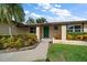 Inviting home entrance with green front door, detailed brick accents, and beautiful, colorful landscaping at 6530 68Th N St, Pinellas Park, FL 33781