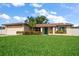 Charming single-story home with a lush green lawn, vibrant landscaping, and a welcoming green front door, set under a blue sky at 6530 68Th N St, Pinellas Park, FL 33781