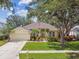 Charming single-story home with a well-manicured lawn, lush landscaping, and a two-car garage at 10203 Shadow Branch Dr, Tampa, FL 33647