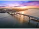 Expansive aerial view of a bridge over the water at sunset, featuring a coastal skyline and vibrant sky at 1109 Pinellas Bayway S # 306, Tierra Verde, FL 33715
