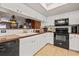 Well-lit kitchen featuring white cabinets, black appliances, and breakfast bar, providing a view into the living area at 1109 Pinellas Bayway S # 306, Tierra Verde, FL 33715