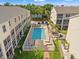 Aerial view of a community pool with lounge chairs, a tiki hut, and well-maintained landscaping between buildings at 1109 Pinellas Bayway S # 306, Tierra Verde, FL 33715