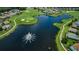 Aerial view of a lake community, featuring a golf course, sand traps, fountain, and well-manicured lawns at 1115 Ashbourne Cir, Trinity, FL 34655