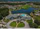 Aerial view showcasing community clubhouse, swimming pool, and surrounding golf course and lake at 1115 Ashbourne Cir, Trinity, FL 34655