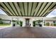 Welcoming covered entryway with brick paving, white pillars, seating, and manicured plants at the community clubhouse at 1115 Ashbourne Cir, Trinity, FL 34655