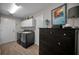 Laundry room featuring gray washer and dryer, overhead cabinet, and a dark dresser at 1115 Ashbourne Cir, Trinity, FL 34655