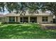 A charming home featuring large windows and a screened lanai, set within a lush green landscape at 1115 Ashbourne Cir, Trinity, FL 34655