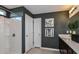 Modern bathroom with a walk-in shower, dark gray walls, and neutral-toned tile floors at 12824 Wanderlust Pl, Parrish, FL 34219