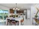A modern kitchen and dining area with stainless steel appliances, a stylish island, a pendant light, and patio access at 12824 Wanderlust Pl, Parrish, FL 34219