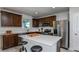 A stylish kitchen featuring dark cabinets, stainless steel appliances, a bright white quartz island, and modern stools at 12824 Wanderlust Pl, Parrish, FL 34219