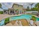Backyard with a sparkling pool surrounded by palm trees, lounge chairs, and travertine tile at 13728 Artesa Bell Dr, Riverview, FL 33579