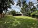 Spacious backyard with lush grass, a screened-in patio, and a wood fence at 1548 Foxboro Dr, Palm Harbor, FL 34683