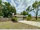 Charming home featuring a two-car garage with a paved driveway surrounded by mature trees and landscaping at 1548 Foxboro Dr, Palm Harbor, FL 34683