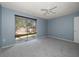 This bedroom features blue walls, a ceiling fan, and a sliding glass door with blinds at 15623 Morgan St, Clearwater, FL 33760
