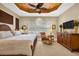 Warm and inviting bedroom with tray ceiling, plantation shutters, and a comfortable chair at 15744 Crystal Waters Dr, Wimauma, FL 33598