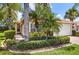 Charming single-story home featuring mature landscaping with palm trees, lush green lawn and a tile roof at 15744 Crystal Waters Dr, Wimauma, FL 33598