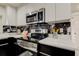Modern kitchen features white cabinets, black accents, stainless steel appliances, and stylish marble-like backsplash at 3025 Palamore Dr, Holiday, FL 34691