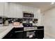 Modern kitchen with white cabinets, black accents, stainless steel appliances, and stylish marble-like backsplash at 3025 Palamore Dr, Holiday, FL 34691