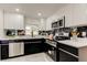 Well-lit kitchen with stainless steel appliances, black and white cabinets, marble backsplash, and quartz countertops at 3025 Palamore Dr, Holiday, FL 34691
