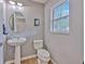 The well-lit half bath features a pedestal sink, decorative mirror, and a window with bright natural light at 3110 Royal Tuscan Ln, Valrico, FL 33594