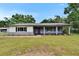 Charming single-story home features a covered porch, red front door and landscaped front yard at 3212 Cork Rd, Plant City, FL 33565