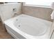 Close up of a pristine white bathtub with chrome fixtures and neutral tile surround, bathed in natural light at 33675 Elm Hill Br, Wesley Chapel, FL 33545