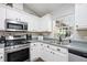 Well-lit kitchen featuring stainless steel appliances, white cabinets, and a view from the window at 37113 Waldo Dr, Dade City, FL 33525