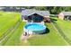 Backyard view of an above-ground pool with a screened-in lanai and fenced yard at 37113 Waldo Dr, Dade City, FL 33525