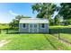 View of backyard shed with double doors, windows and gray siding on a sunny day at 37113 Waldo Dr, Dade City, FL 33525