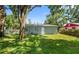 Backyard view with a well-maintained lawn, mature trees, and a glimpse of the home's exterior at 3907 W Walnut St, Tampa, FL 33607
