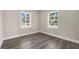 Empty bedroom with wood-look floors, light walls, and two windows at 3907 W Walnut St, Tampa, FL 33607