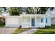 Charming home with a blue front door, white railing, and a walkway through the landscaped front yard at 3907 W Walnut St, Tampa, FL 33607