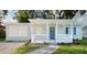 Charming home with a blue front door, white railing, and a walkway through the landscaped front yard at 3907 W Walnut St, Tampa, FL 33607